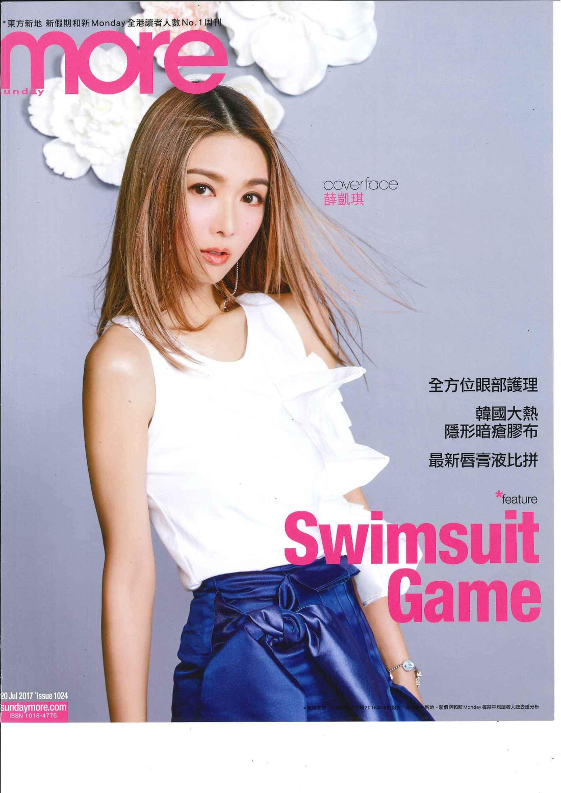 Woman in white ruffled top and blue skirt posing on magazine cover with swimsuit feature