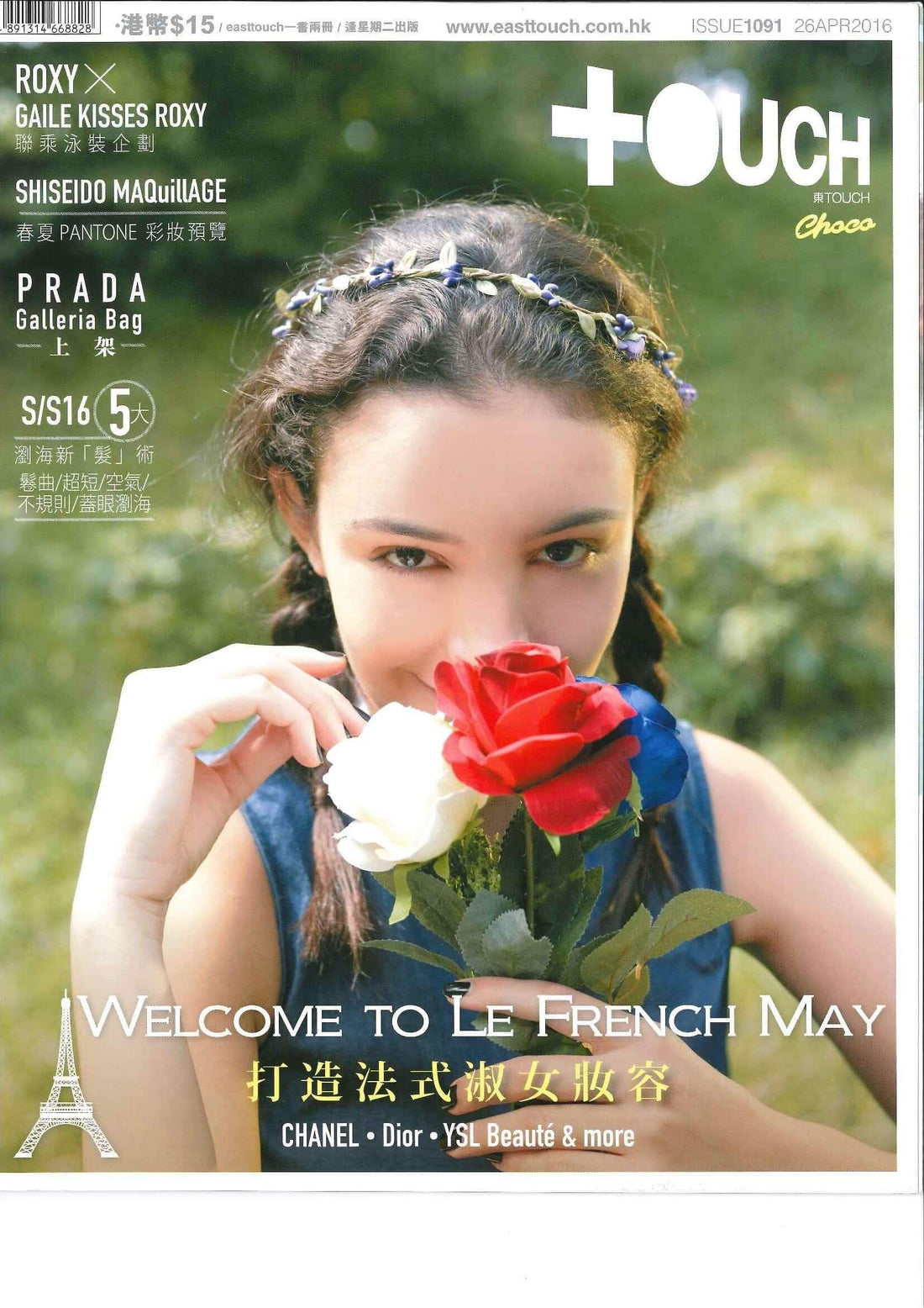 Woman in outdoor setting holding red, white, and blue flowers, wearing braided hair with floral headband