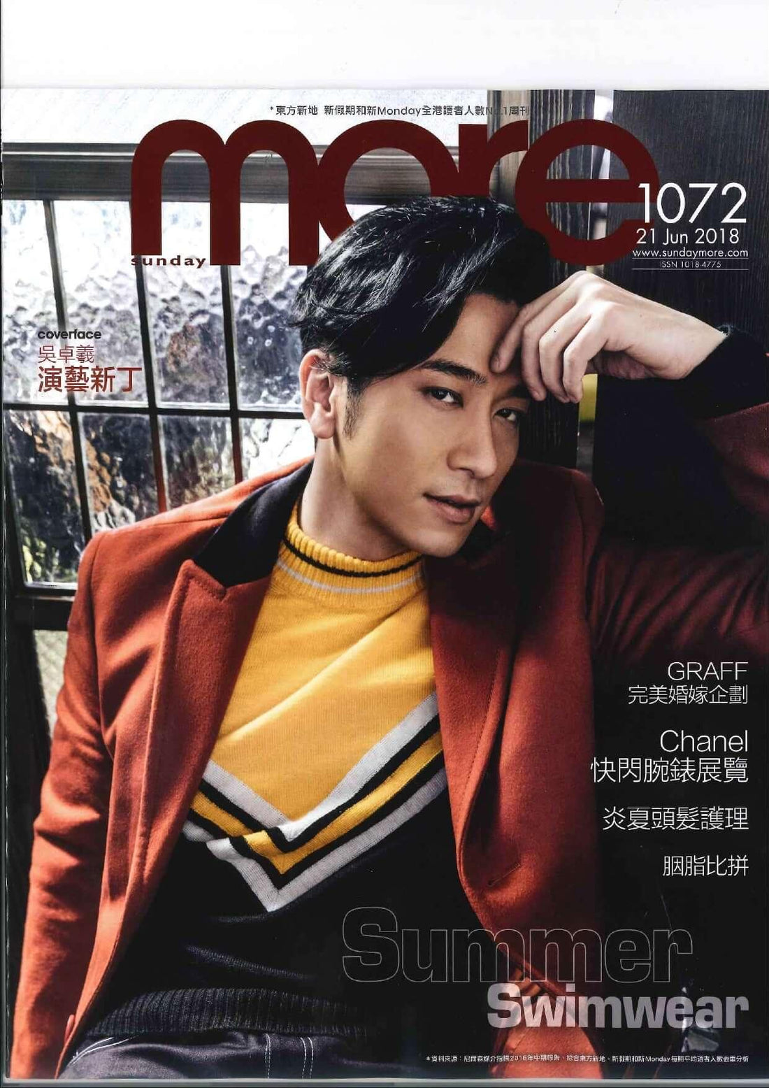Man in yellow and black sweater with orange blazer, sitting indoors for magazine cover
