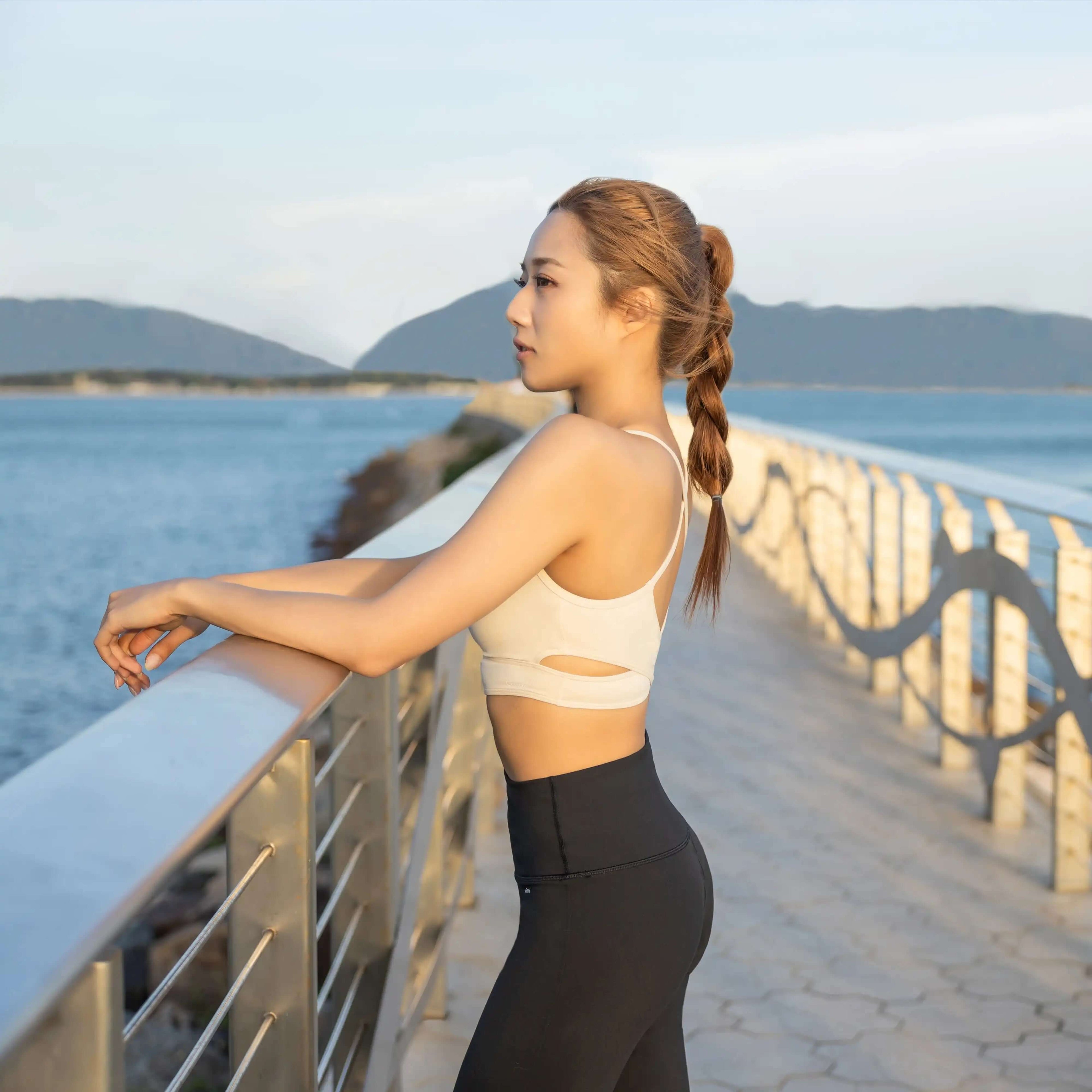 Woman in activewear by waterfront, perfect for yoga or gym workouts