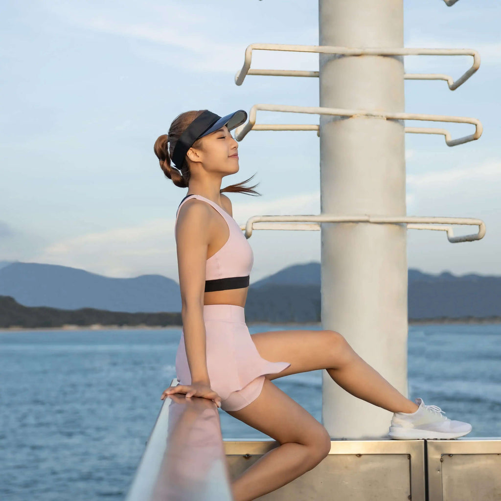 Woman enjoying the outdoors in a Balance Skort, paired with a sporty top and visor near the water.