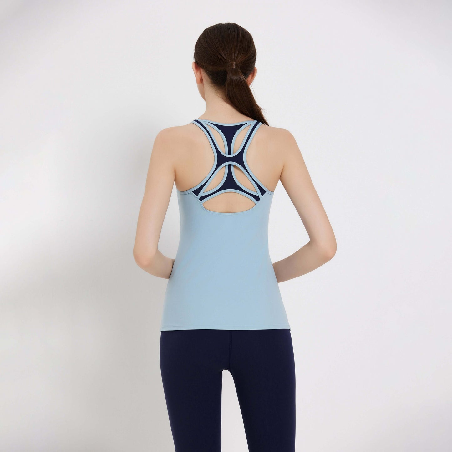 Back view of a woman wearing a blue Impact Tank Top with stylish racerback design, perfect for workouts.