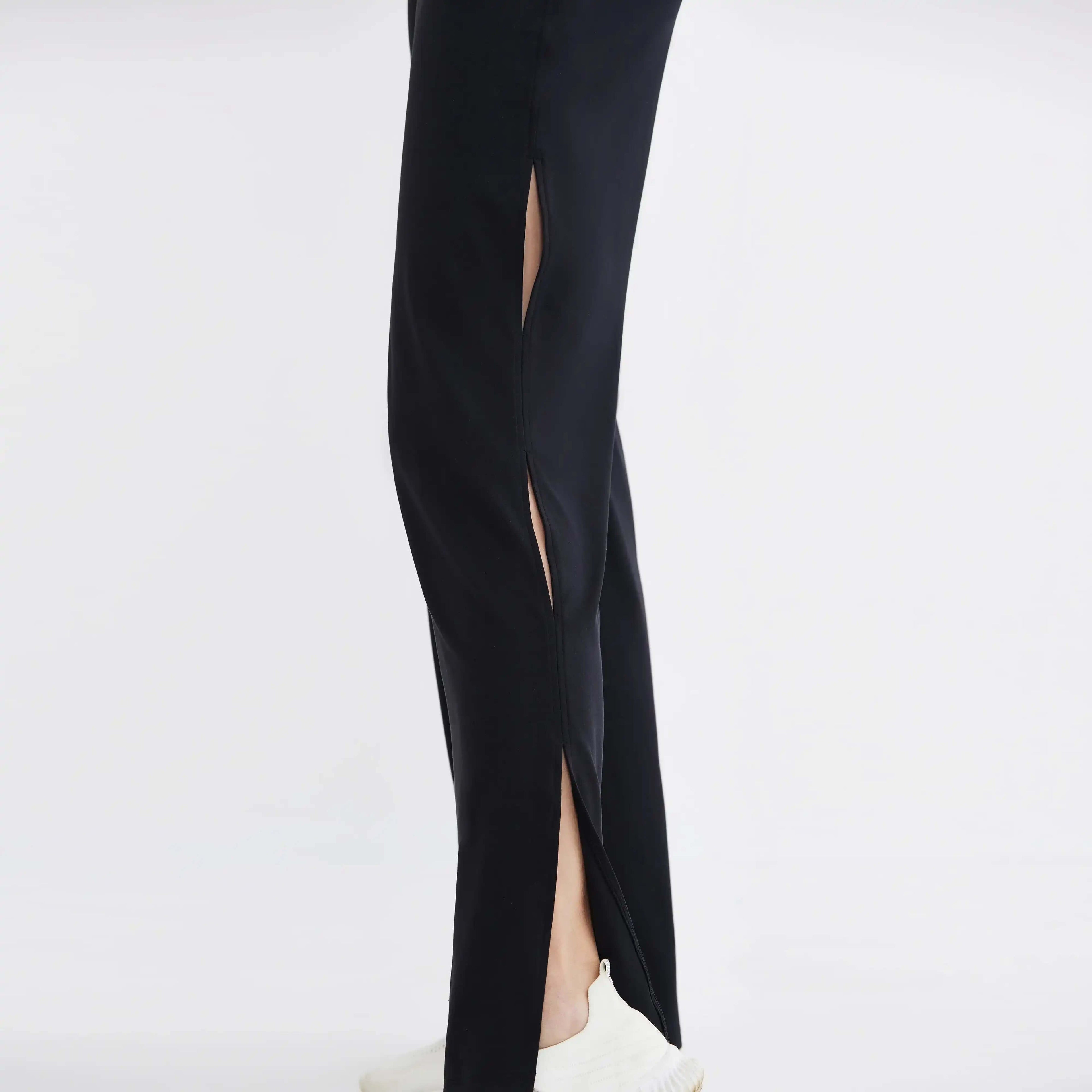 Black high-performance activewear pants with side slits, shown with white sneakers