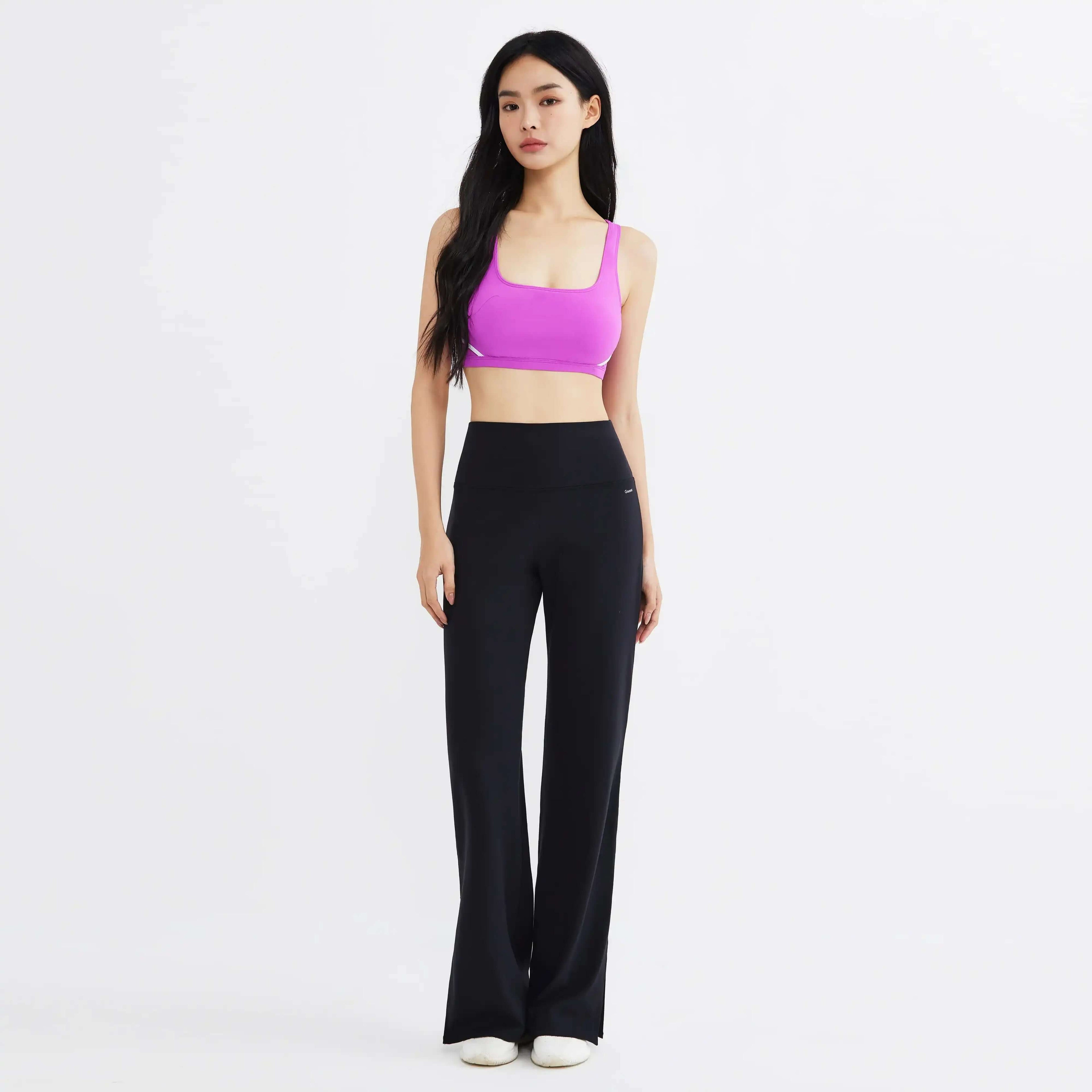 Woman in magenta sports bra and black high-waisted yoga pants, studio background