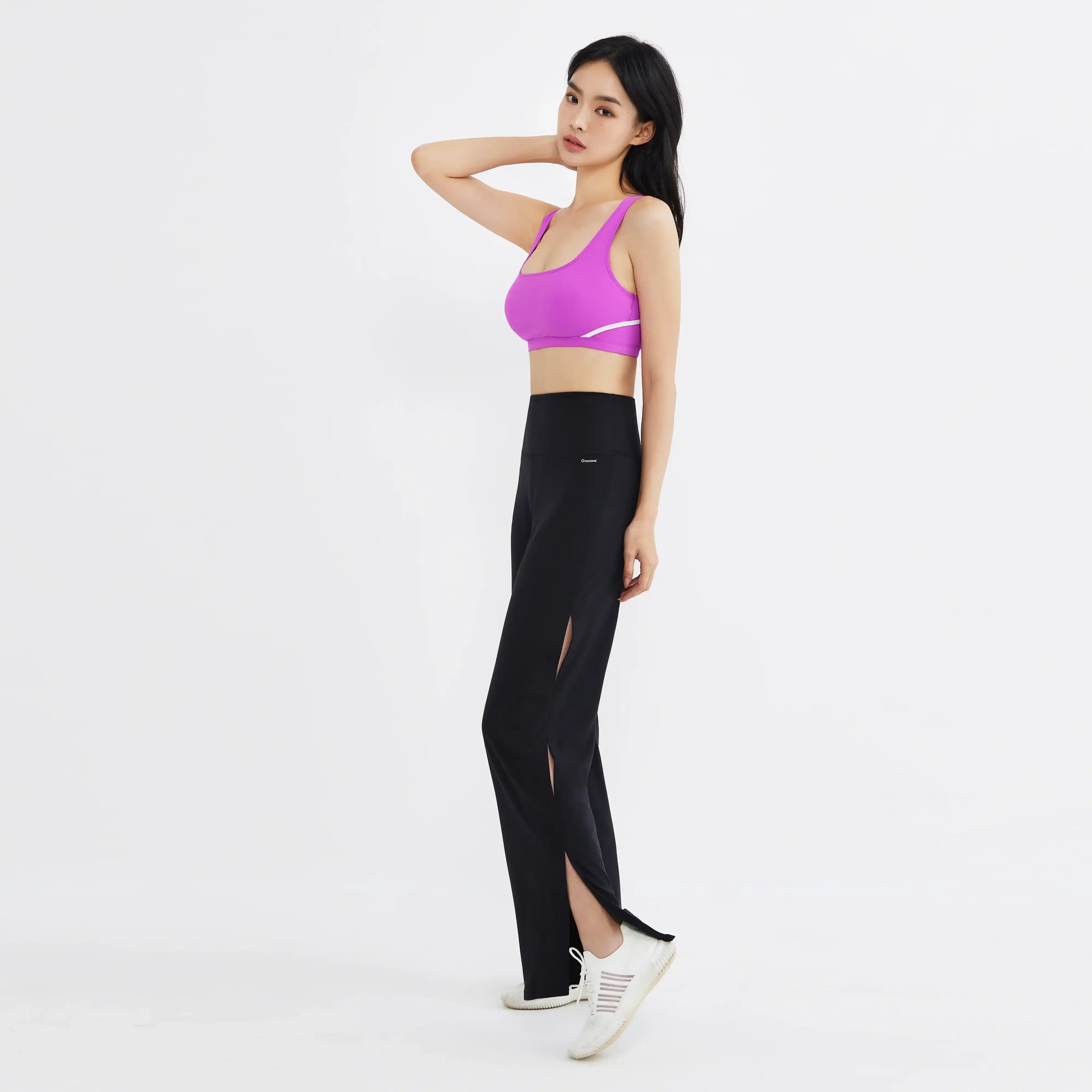 Woman in a purple sports bra and black high-waisted slit yoga pants with white sneakers