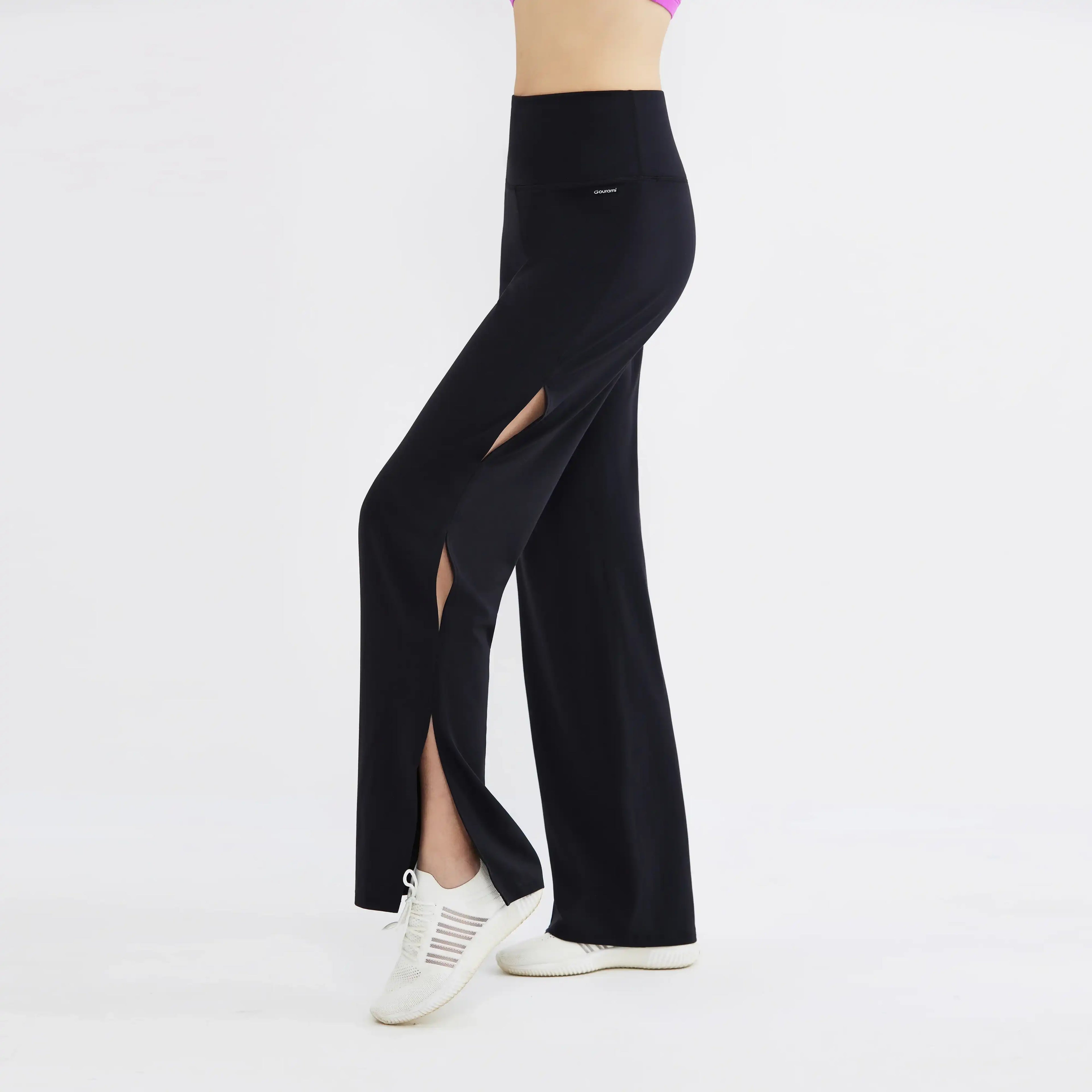 Black high-waisted activewear pants with front leg slits, worn with white sneakers