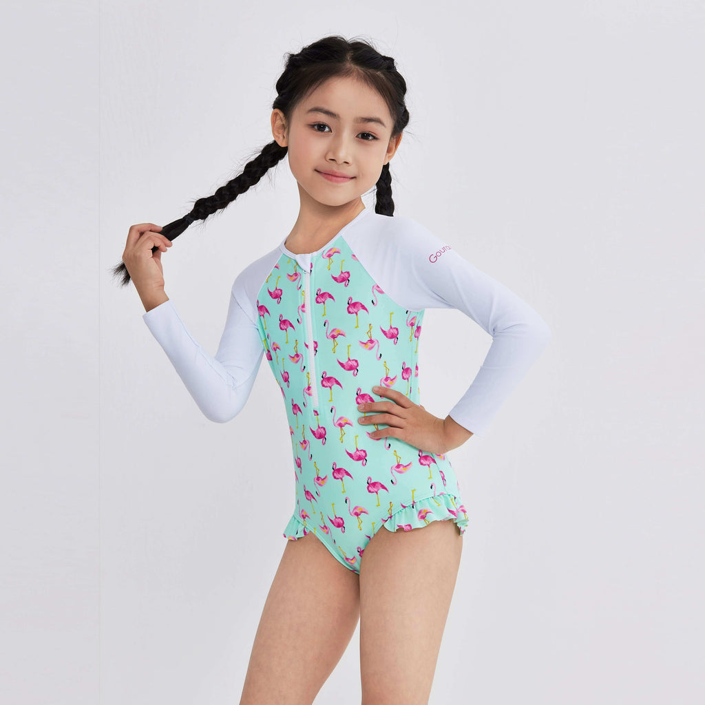 Girl in flamingo print long sleeve swimwear with ruffle hem, designed for active water play.