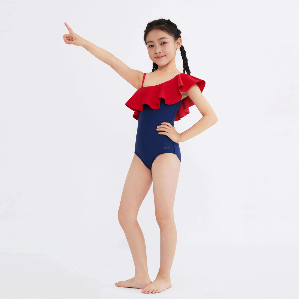 Girl in navy one-piece swimsuit with red ruffle shoulder, designed for active movement and style.