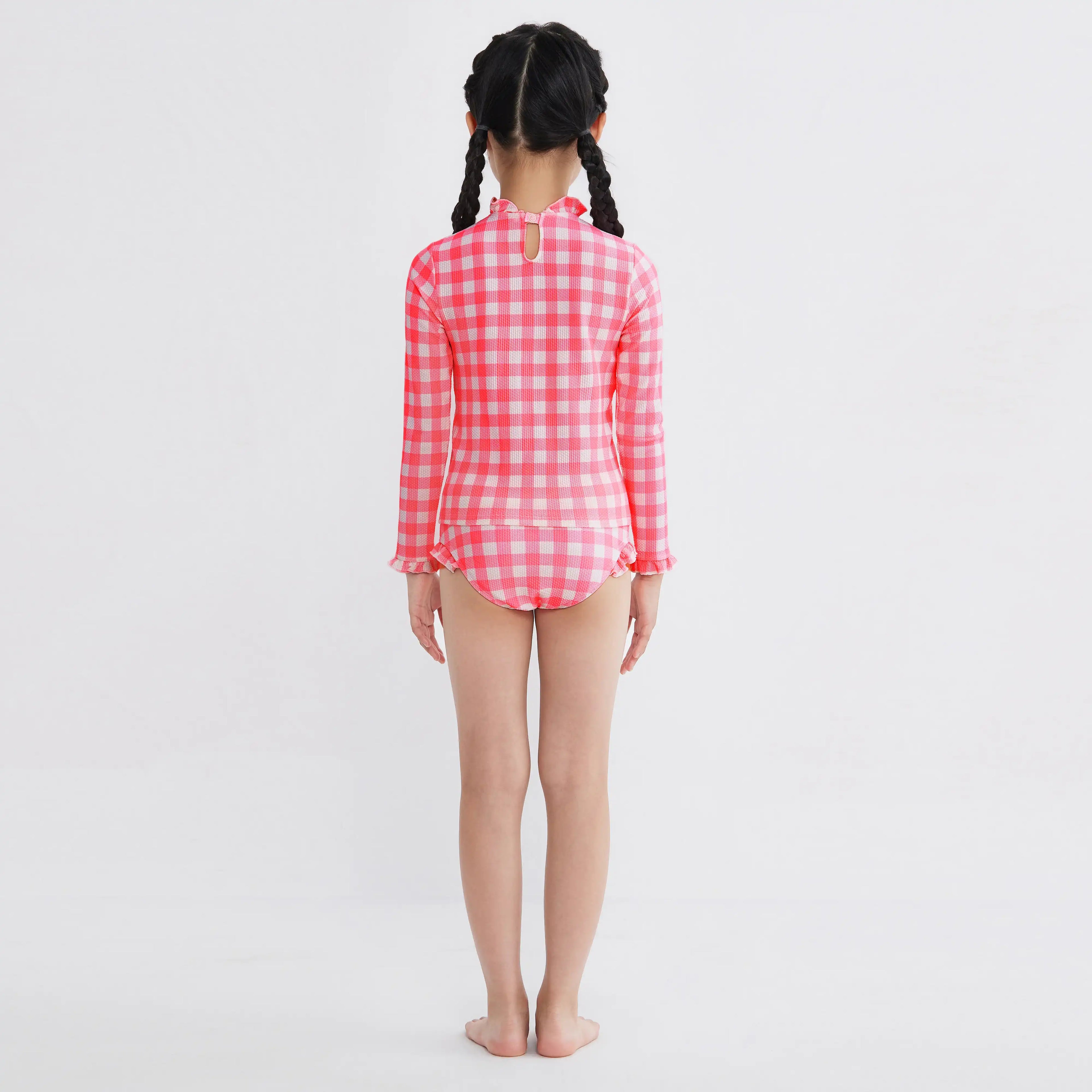 Girl in pink gingham long-sleeve swimsuit with ruffles, back view