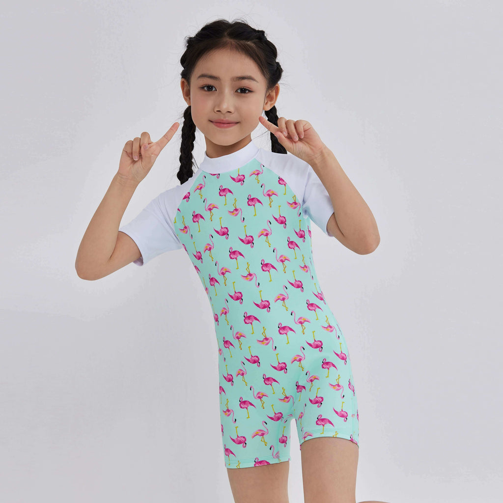 Girl in mint green flamingo print rash guard with white sleeves, perfect for swim and active play.