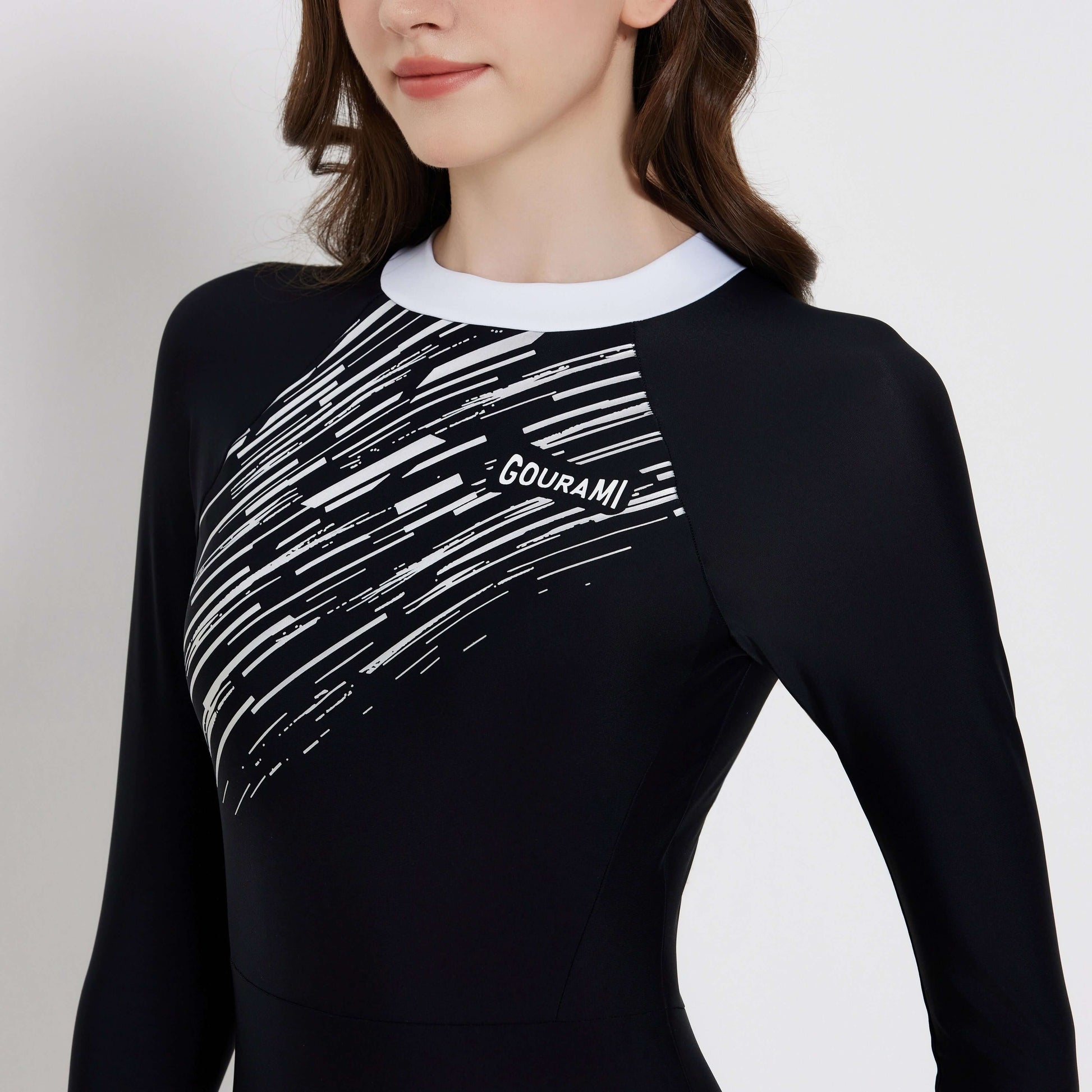 Model wearing the Meteor Long Sleeve Swimsuit featuring a stylish black and white design, perfect for beach activities.