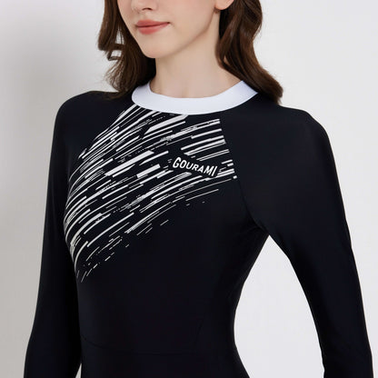Model wearing the Meteor Long Sleeve Swimsuit featuring a stylish black and white design, perfect for beach activities.