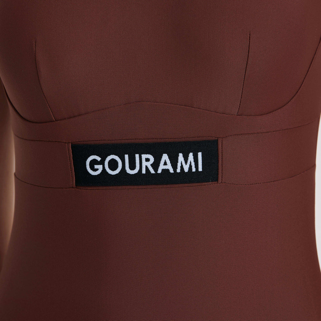 棕色面料上带有 Gourami 标志的 G Sport 泳衣特写。