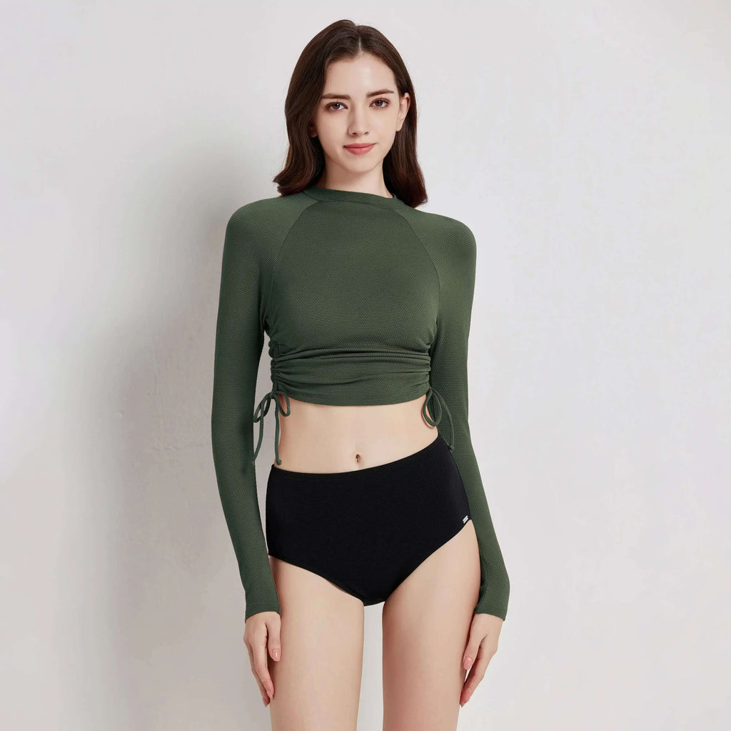 Model wearing Flowform Rashguard Set featuring a green long-sleeve top and black high-waisted bottoms.
