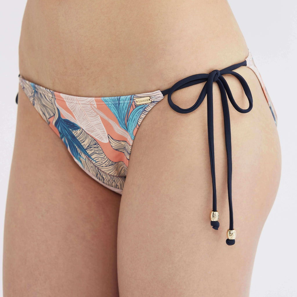 Tropical print bikini bottom with navy side ties and gold accents, designed for comfort and style.