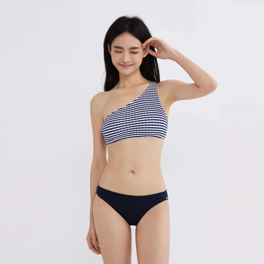 一名女子身穿海军蓝和白色条纹比基尼，背景为白色