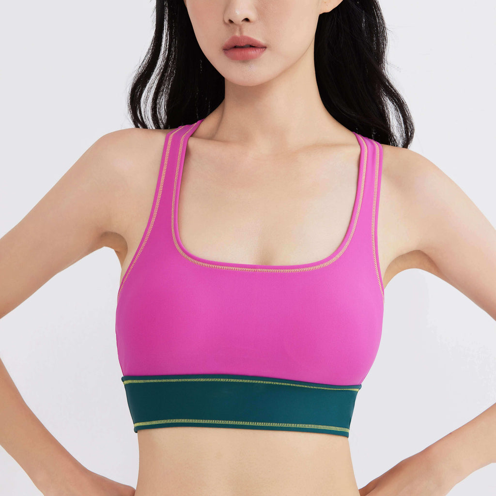 Vibrant pink and green activewear sports bra with gold stitching, designed for performance and style.