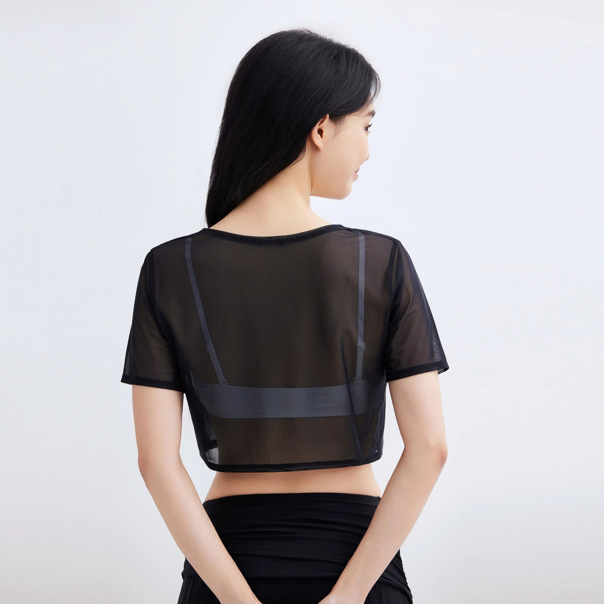 Back view of a woman wearing a Gourami Drift black sheer mesh coverup top.