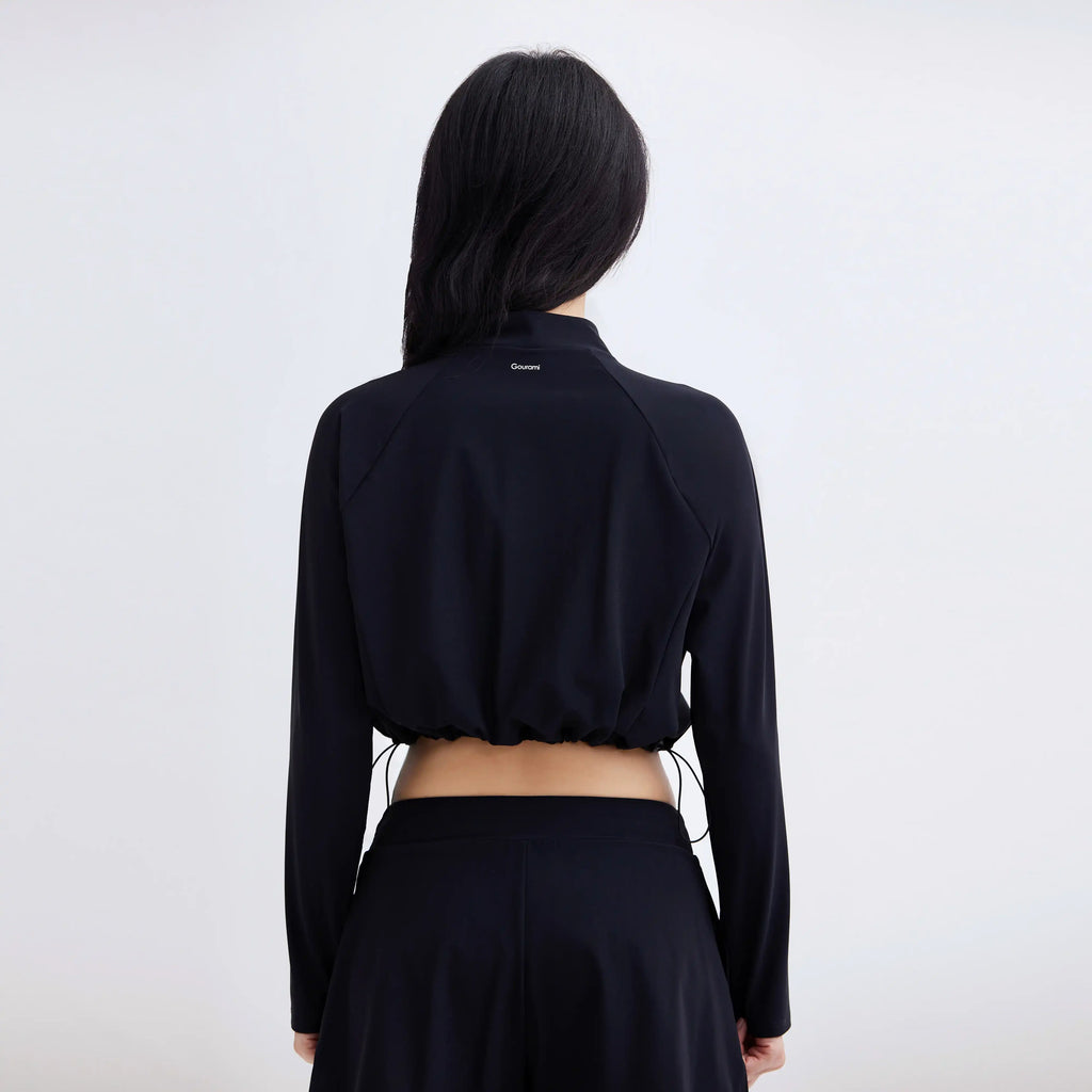 Back view of a woman wearing a black Gourami Drift Gym To Swim cropped jacket and matching pants.