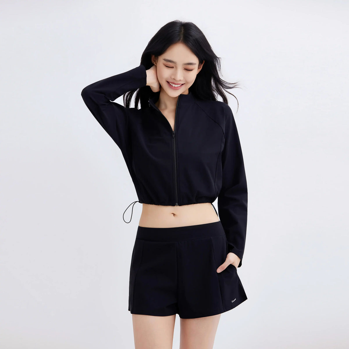 Woman wearing a black Gourami Drift Gym To Swim Jacket and matching shorts.