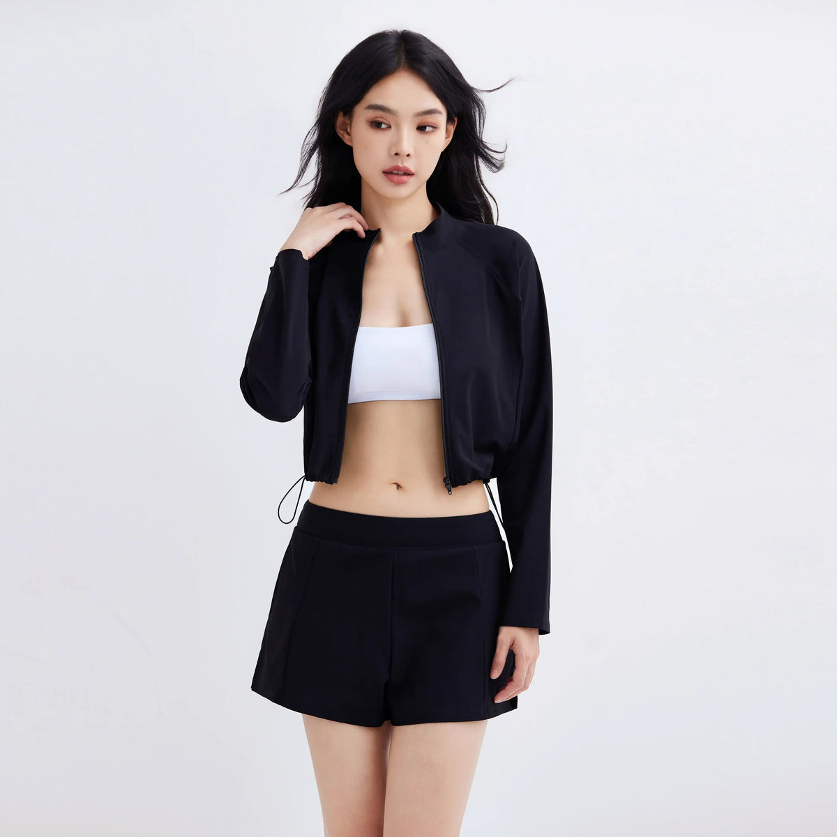 Woman wearing a Gourami Drift Gym To Swim Jacket with matching black shorts and white sports bra.
