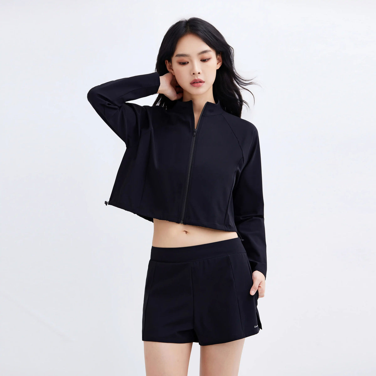 Woman wearing Gourami Drift Gym To Swim black cropped zip-up jacket and matching shorts.