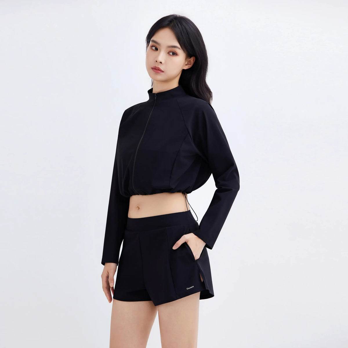 Woman wearing a black Gourami Drift Gym To Swim Jacket and matching athletic shorts.