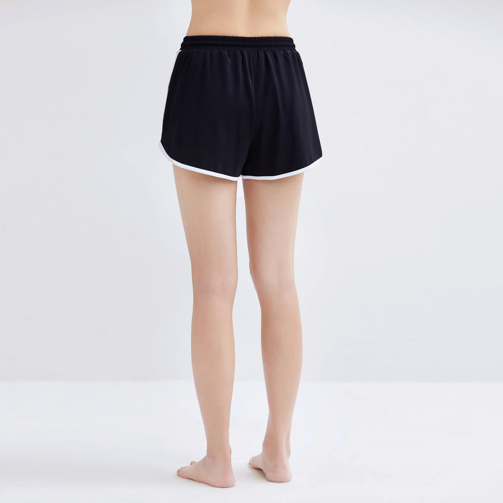 Rear view of a woman wearing black Contrasting Swim Shorts with white trim.