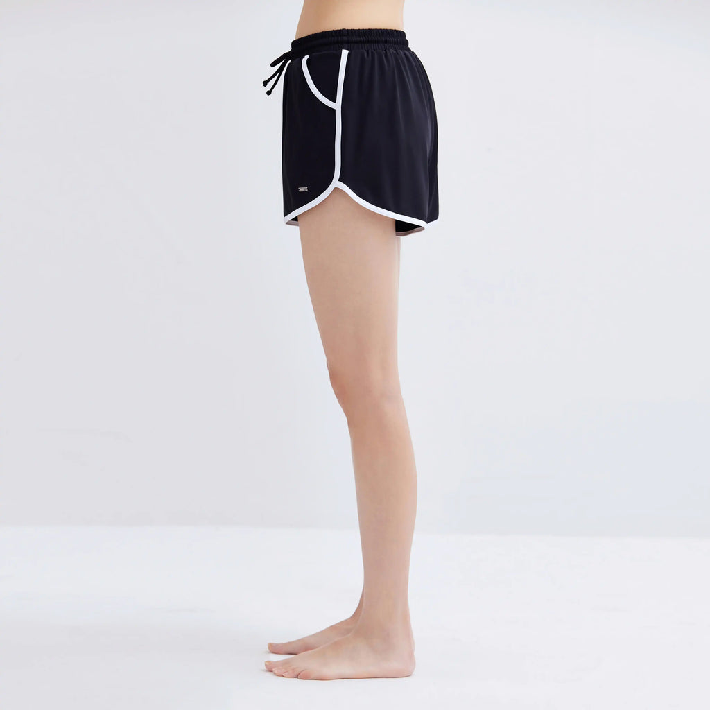Side view of a woman wearing black Contrasting Swim Shorts with white trim.