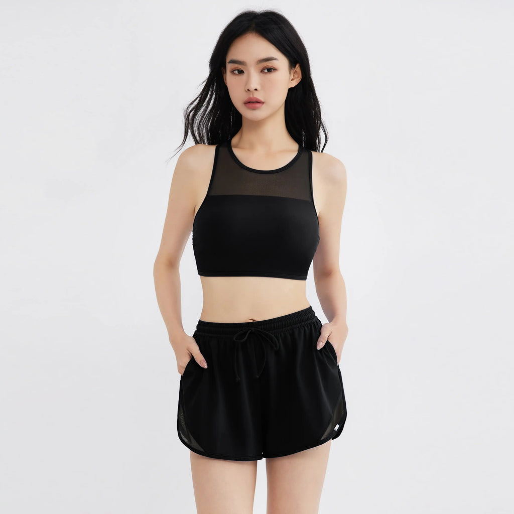 Woman modeling black mesh-paneled sports bra and drawstring shorts, designed for active movement and comfort.