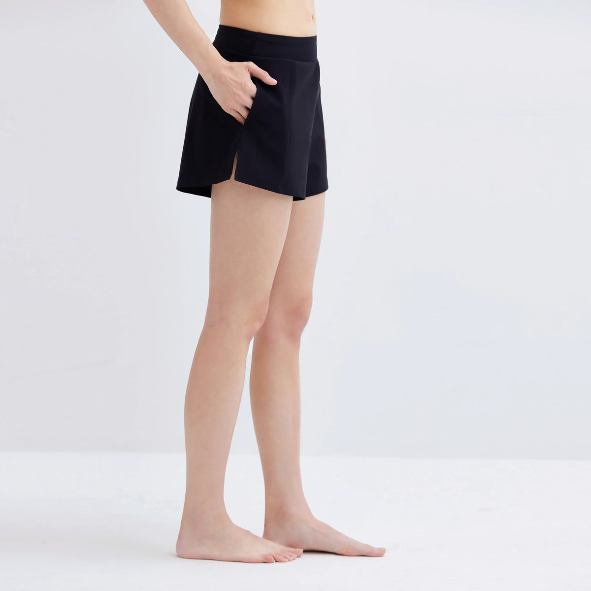 Side view of a woman wearing black Gourami Drift Gym to Swim Shorts.