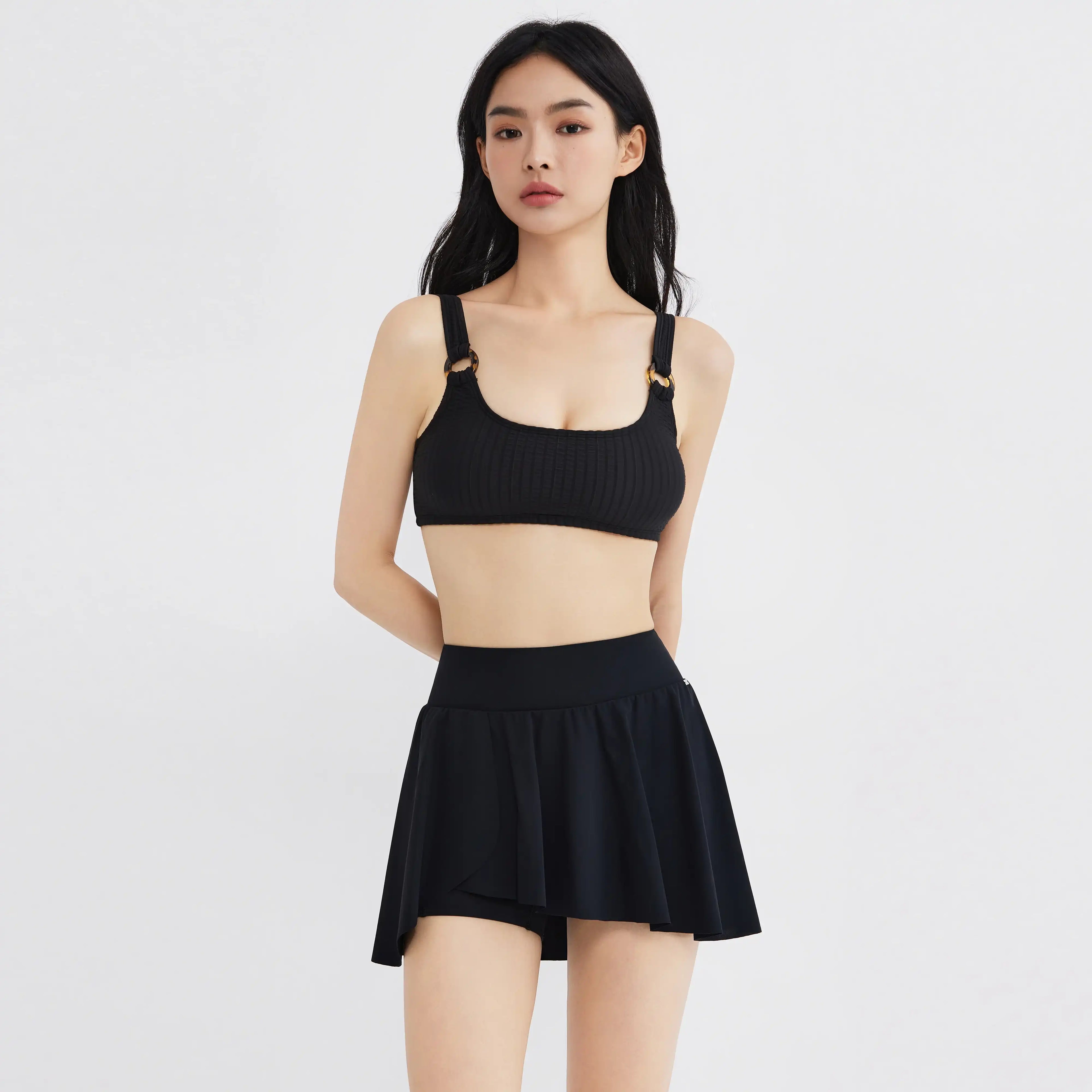Black ribbed bikini top with gold rings and flared skirt bottom for swimwear