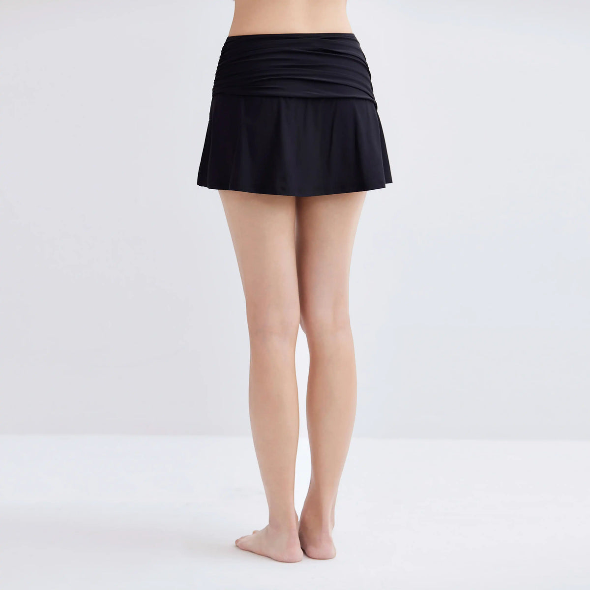 Back view of a woman wearing a black Gourami Tuck Swim Skirt.