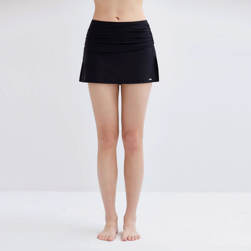 Woman wearing a black Gourami Tuck Swim Skirt against a plain white background.