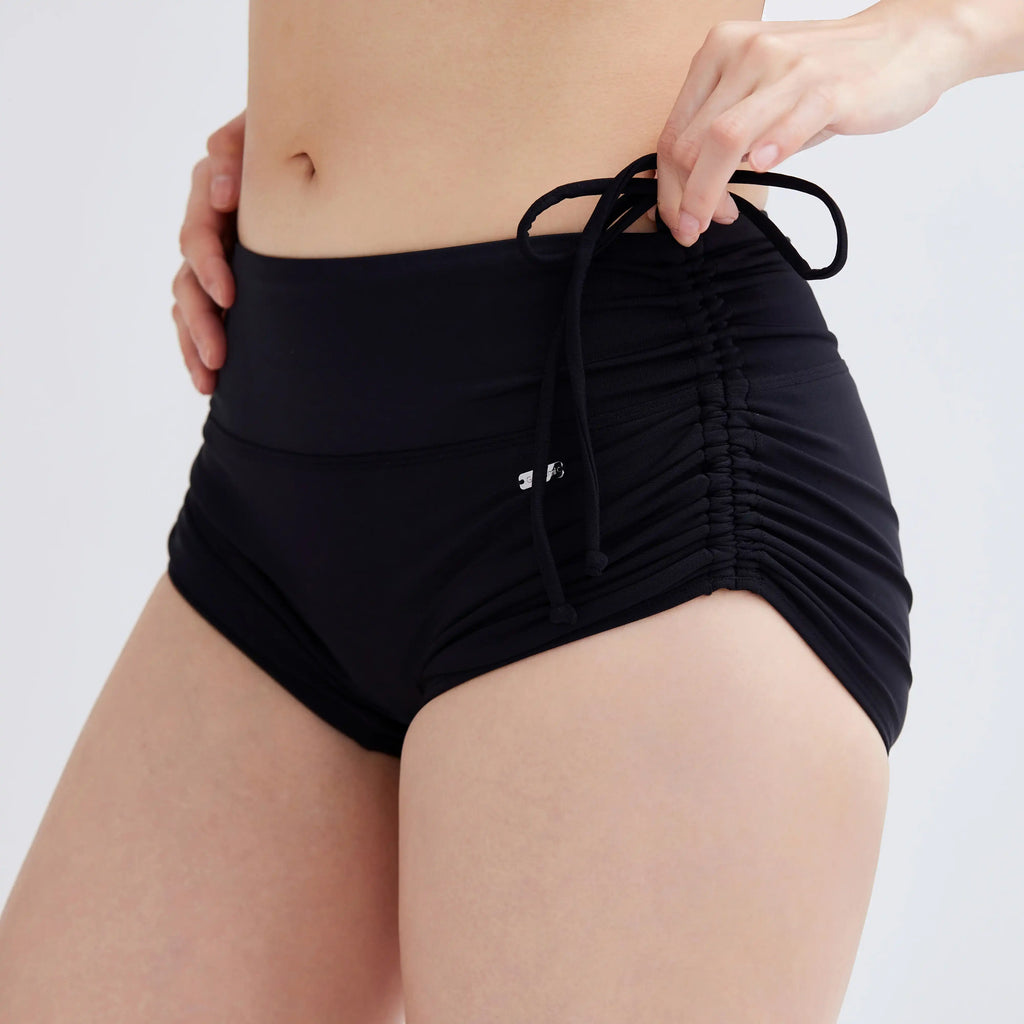 Woman wearing black Swim Fit Ladies Scrunchie Shorts with a drawstring waist.