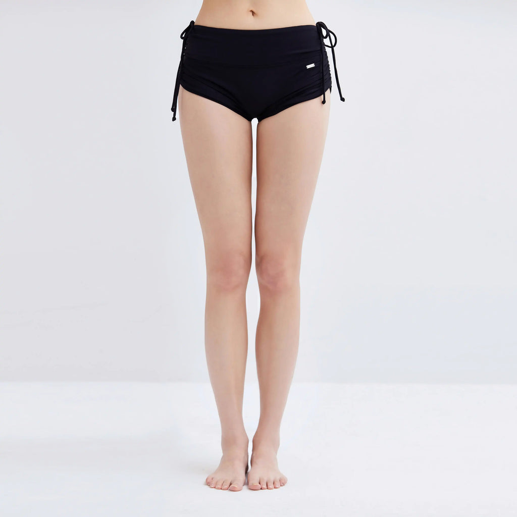 Woman wearing black Swim Fit Ladies Scrunchie Shorts with side tie details.