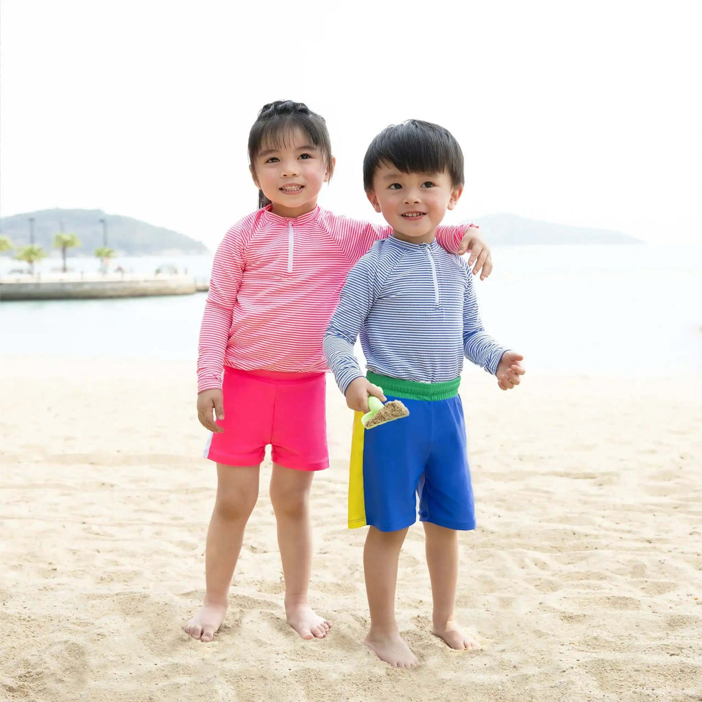 Children wearing Candy Stripe Boys Rashguard Set at the beach, enjoying a sunny day.