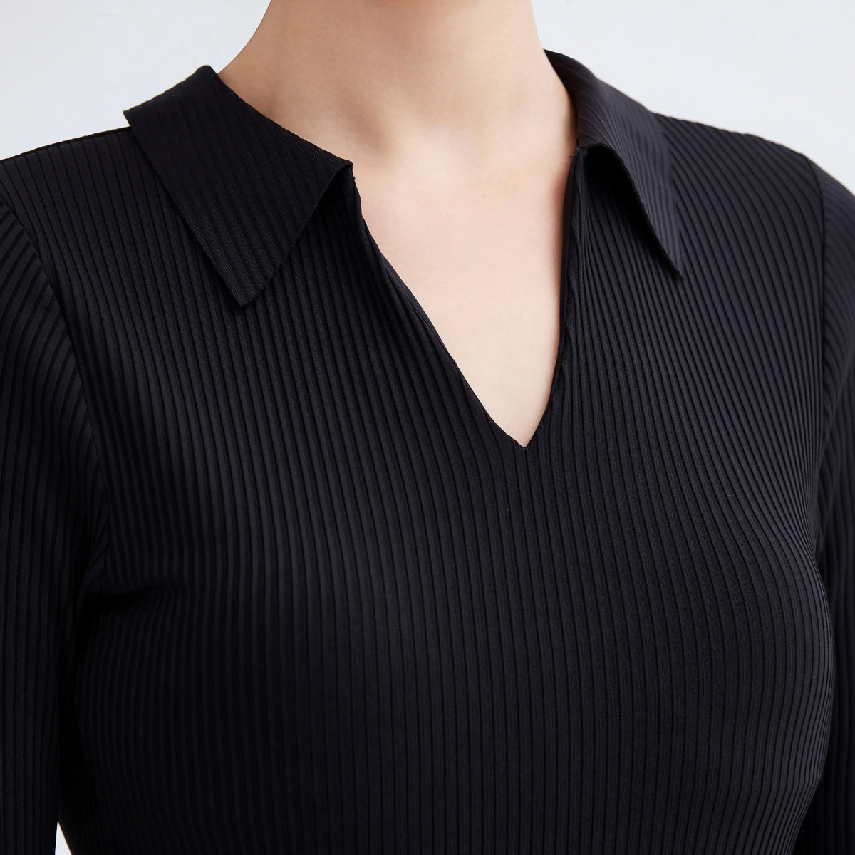 Close-up of a black ribbed Gourami capsule long sleeve swimsuit with a collar and V-neckline.